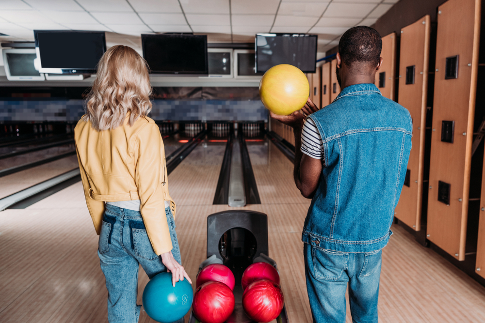 Couple holding bowling balls at a bowling alley