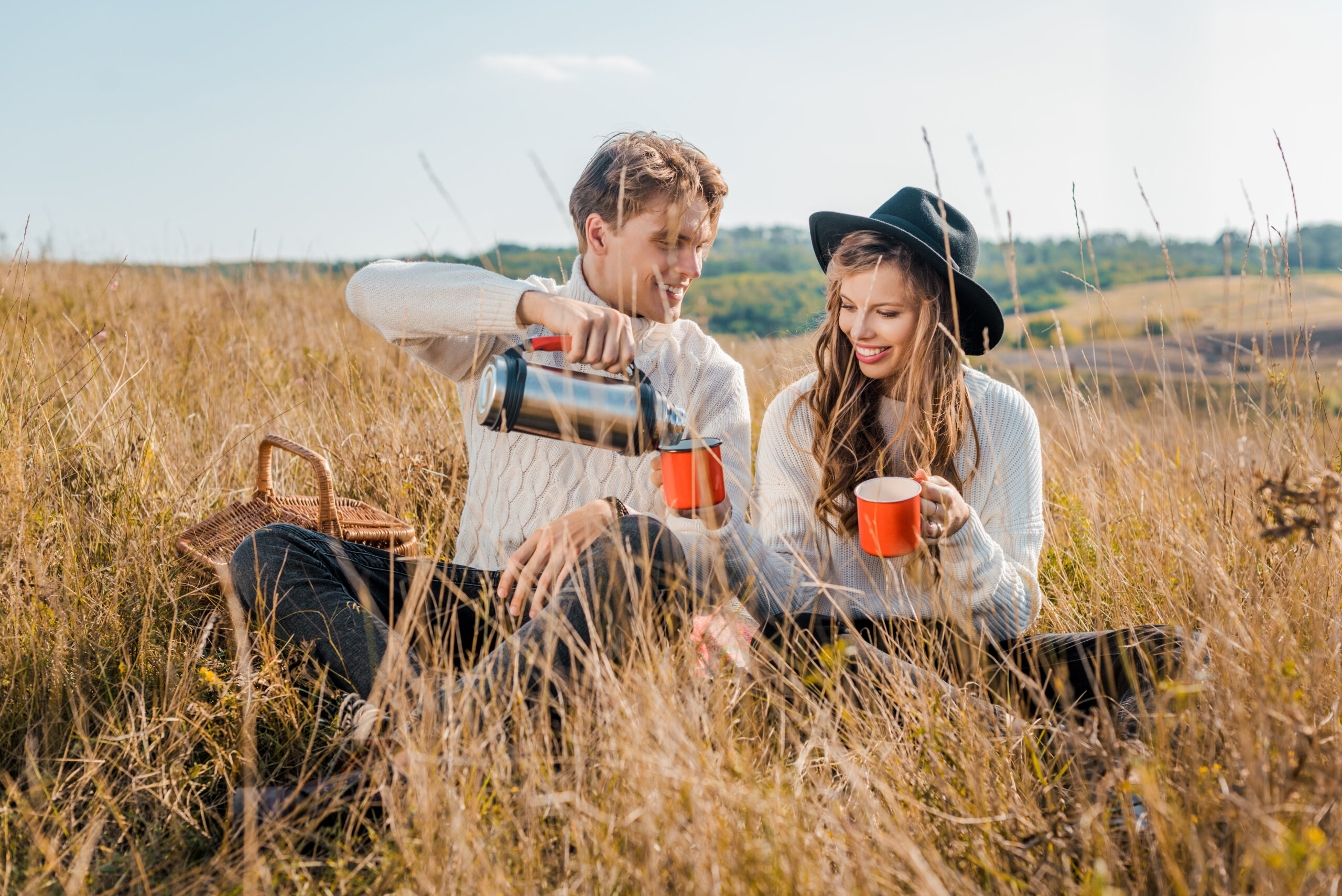 questions to ask before getting married - couple enjoying coffee in field with tall yellow grass