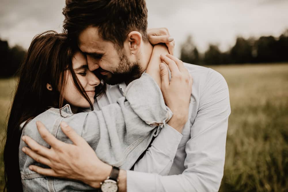 how to be a better husband - dark haired couple embracing in field