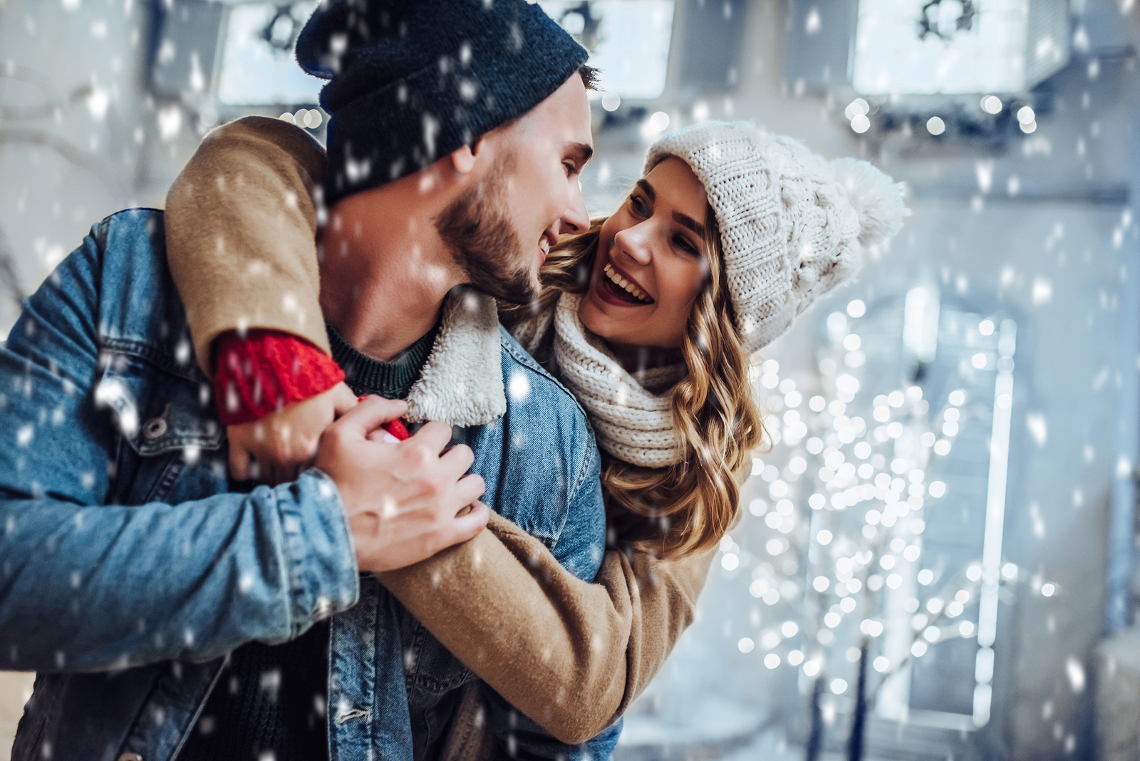 winter bucket list - couple hugging in winter clothes with sparkly snowflakes around them