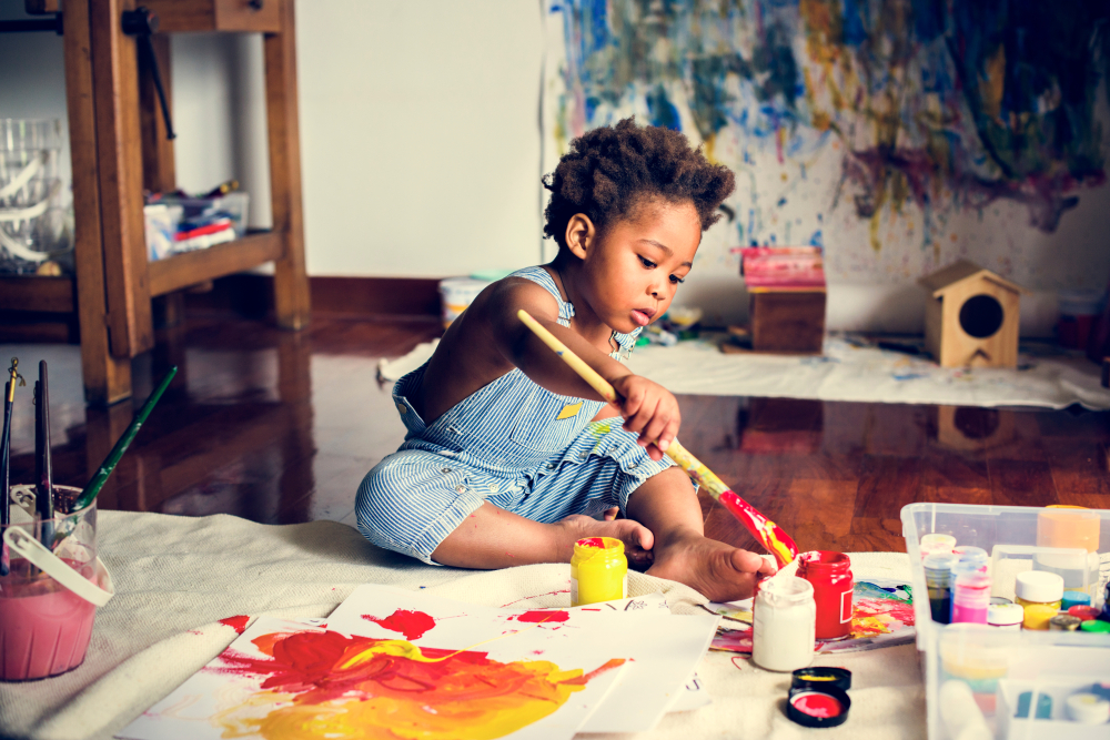 Child painting with red and yellow paint