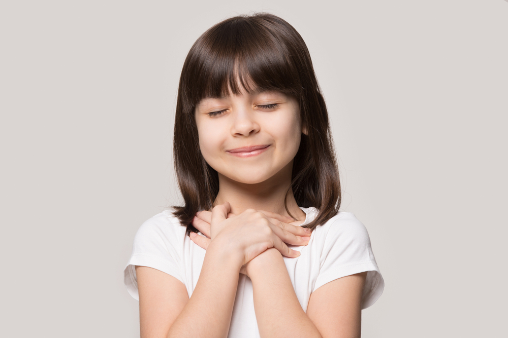 Little girl with her eyes closed and her hands crossed on her chest