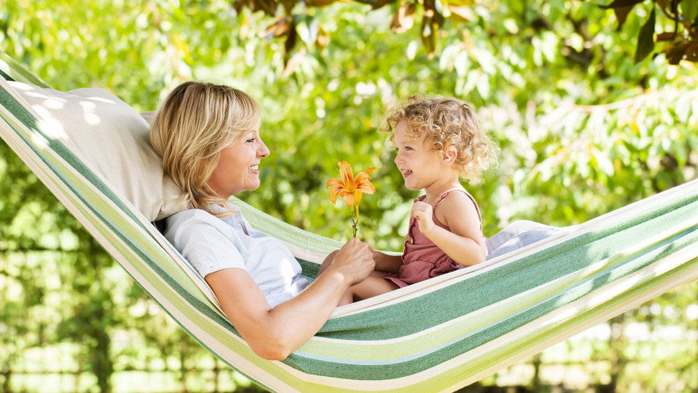 Mom and child sitting in a green hammock with smiles