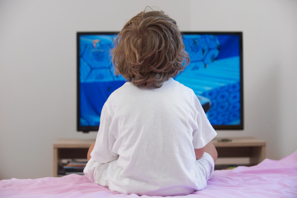 Child on a bed watching tv