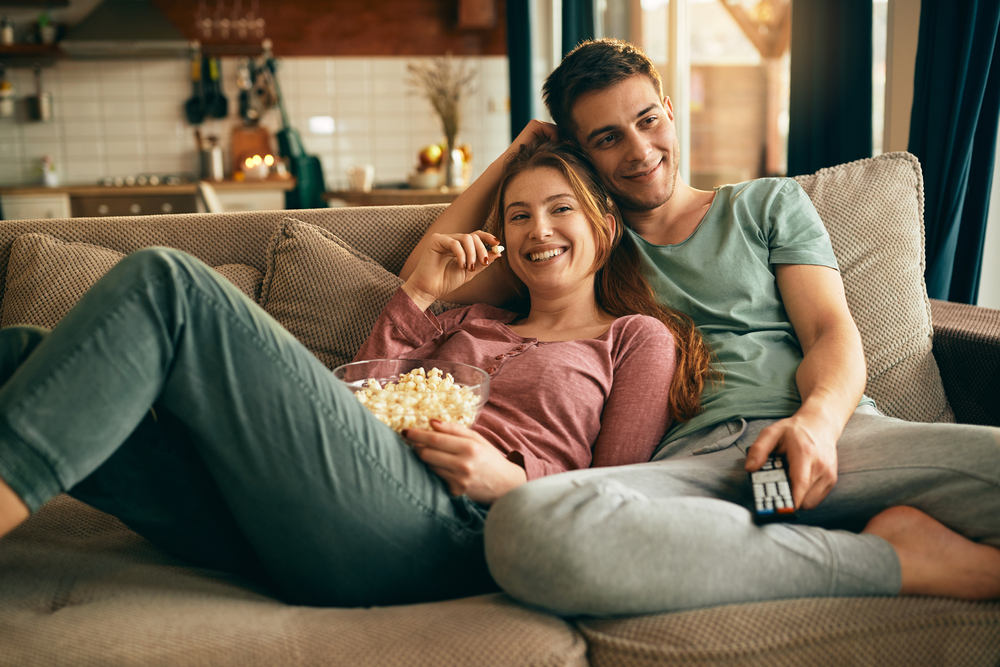 Two people eating popcorn on a couch